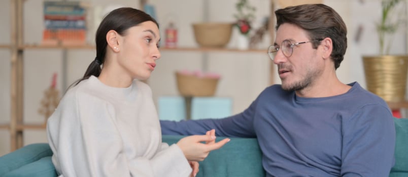 Couple sitting on couch having conversation 