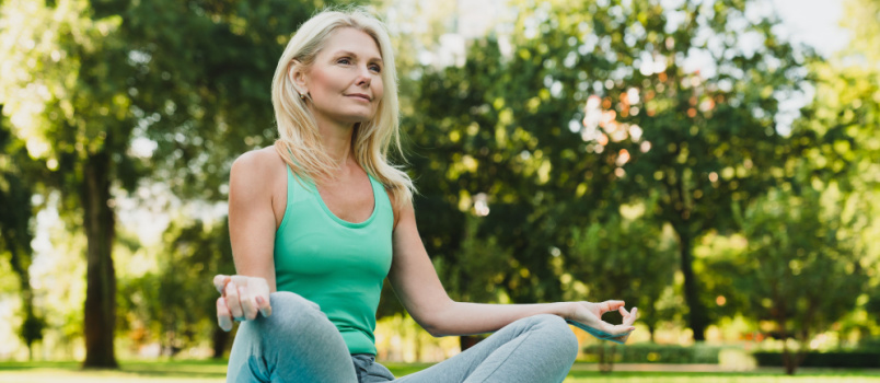 Mature woman doing meditation sitting in nature
