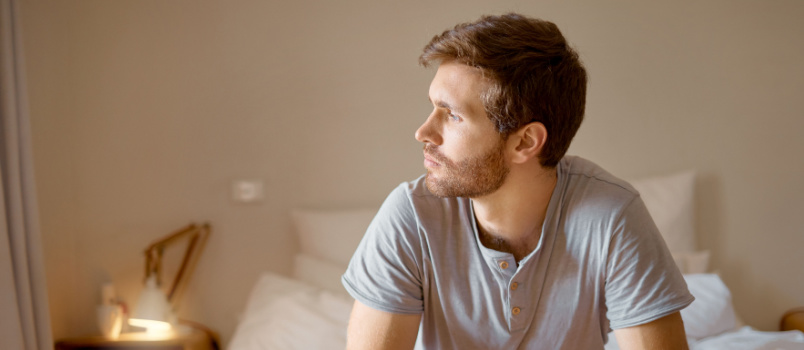 Sad depressed man sitting on bed