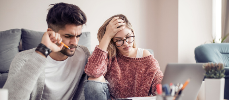 Lovely couple sitting at home looking at laptop