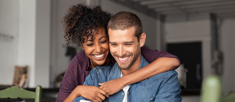 Young couple embracing while looking in laptop