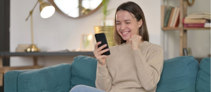 Young woman celebration success on smartphone