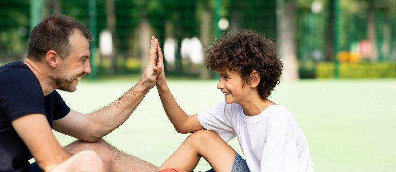 Un père et son enfant partagent un joyeux High Five en plein air
