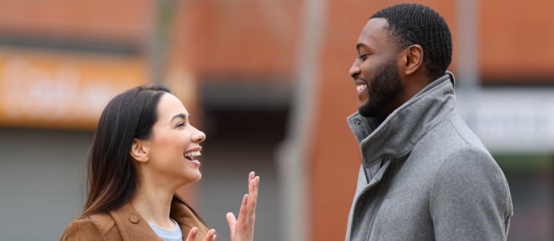 Young woman laughing while standing with black man