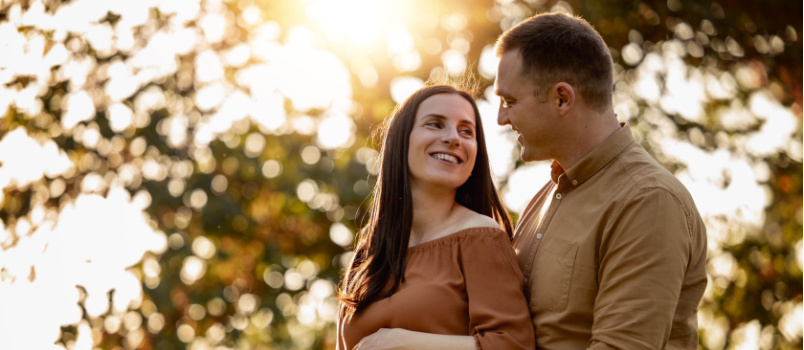 Happy pregnant couple standing outside in nature