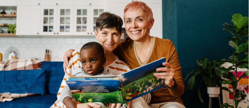 Lesbian couple reading book with kids