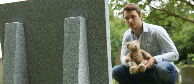 Father placing teddy on child funeral
