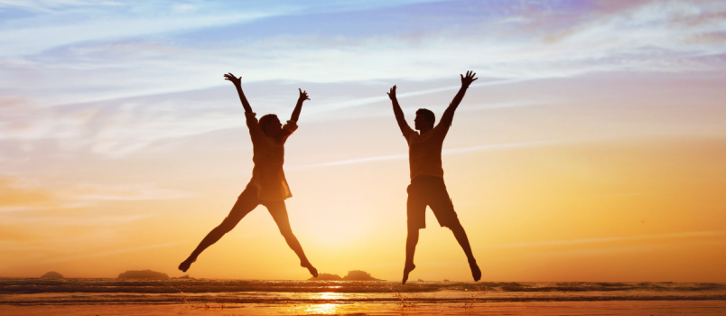 Happy couple jumping on beach sunset