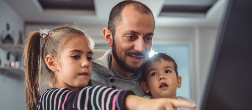 Two children watching tv with her dad