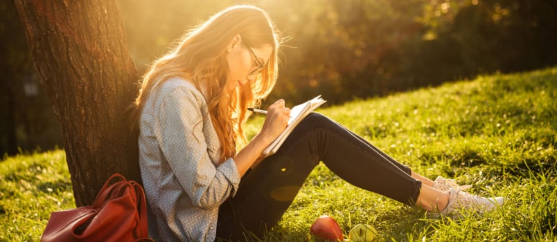 Woman sitting under tree working