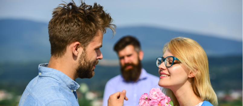 Young couple dating while jealous man looking at them
