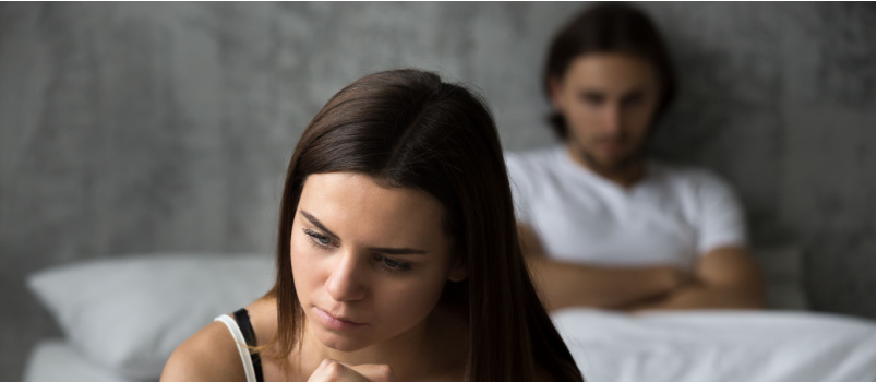 Frustrated couple sitting on bed