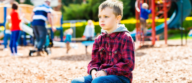 Sad boy sitting alone in park