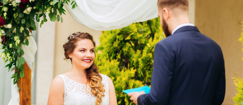 Beautiful bride standing near decorated arch