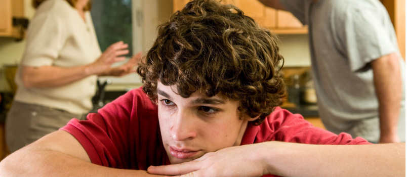 Sad boy laying while parents having argument