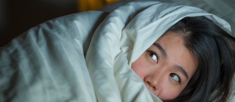 Young sleepful woman laying on bed