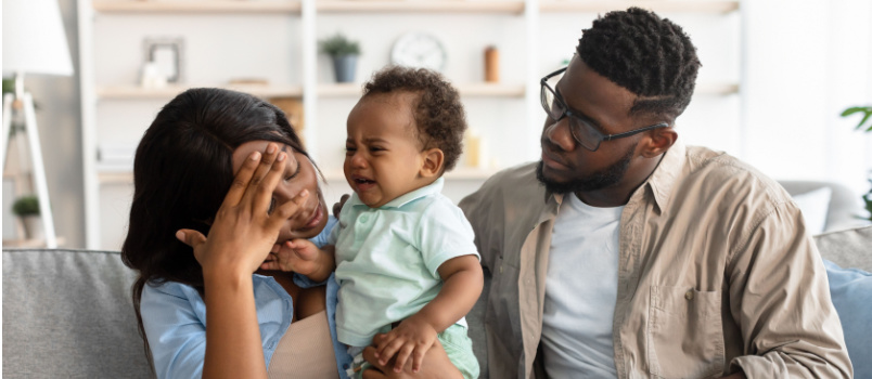 Tired mother sitting with her baby and husband