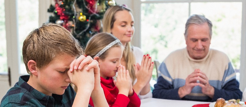 Young couple doing prayer before having meal