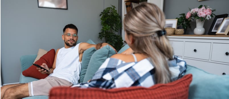 Young couple sitting on couch talking to each other