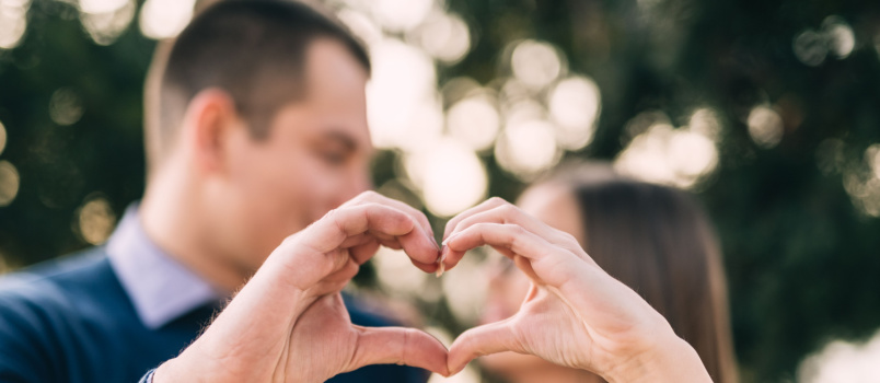 Young couple making heart with hand