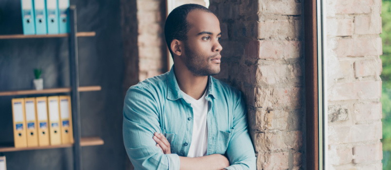 Serious freelancer standing by wall
