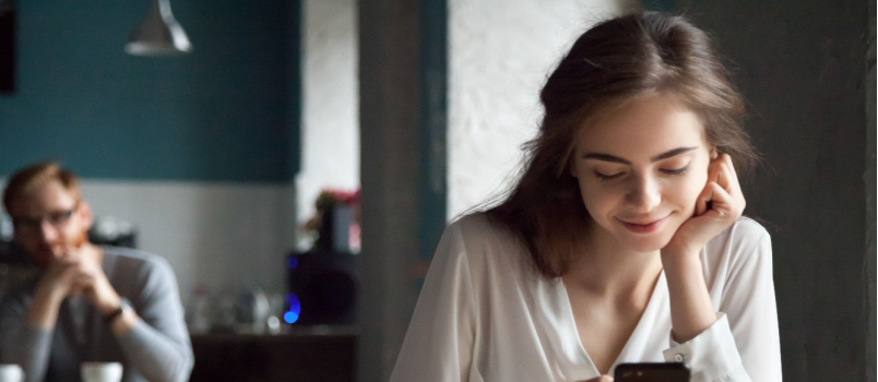 Curious guy looking at girl using smartphone