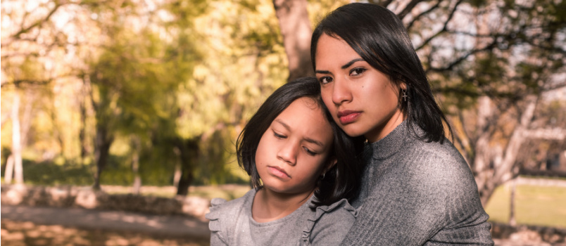Serious woman embracing her daughter