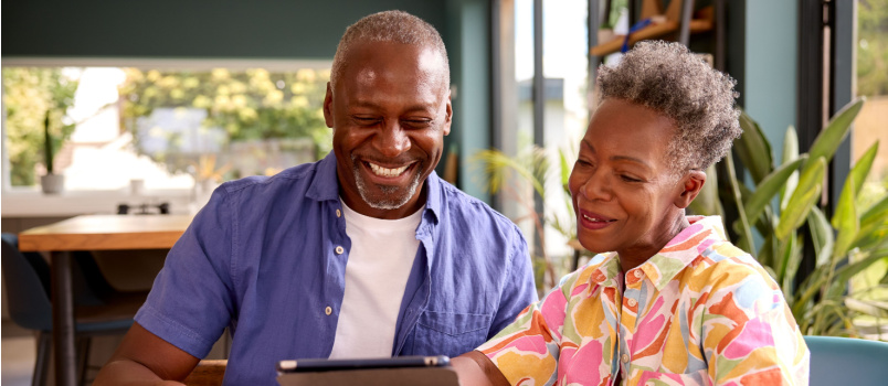 Senior couple sitting using tablet