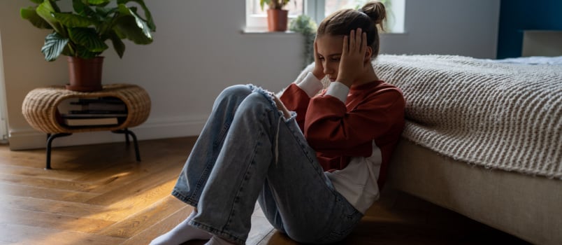 Sad teen child sitting on floor