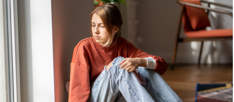 Upset teen girl sitting on floor