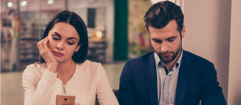 Bored couple sitting using smartphone