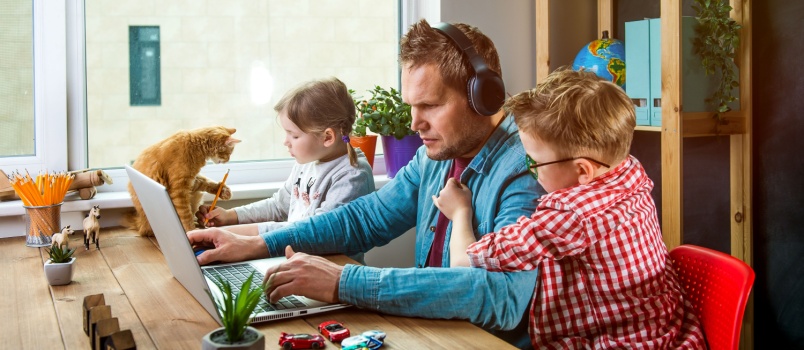 Man working on laptop while handling kid