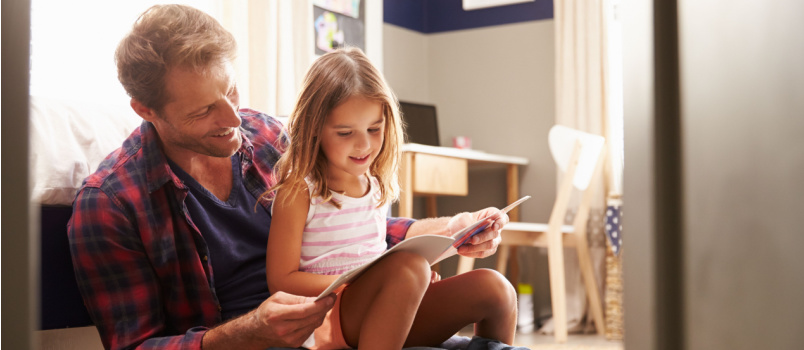 Father and daughter reading book together