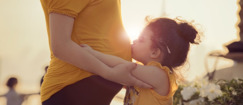 Daughter kissing mom belly