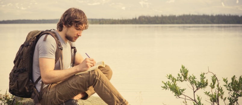 Young man travelling sitting reading book