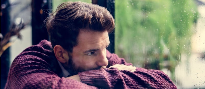 Sad man looking outside window