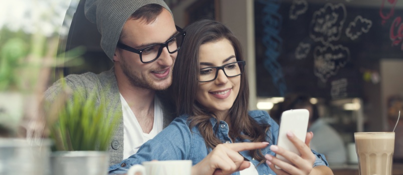 Couple using phone sitting in cafe