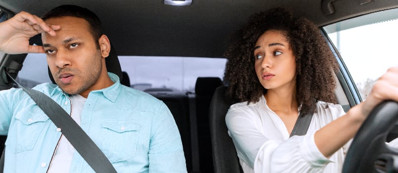 Wife drivinig & looking at angry husband