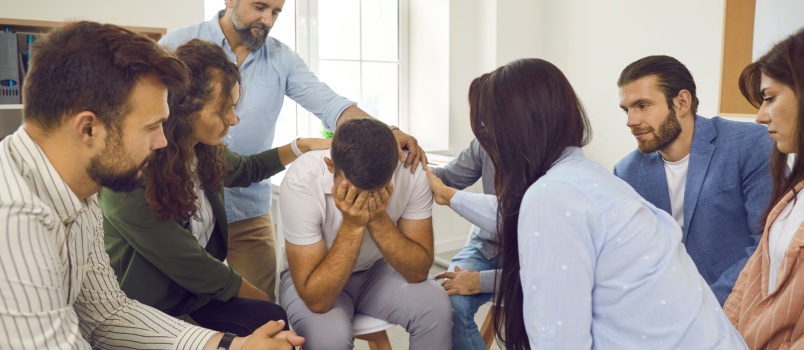 Group of friends consoling sad man