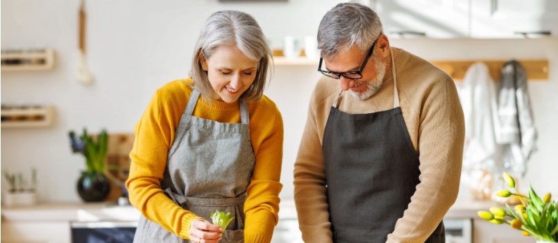 Happy elder couple cooking in kitchen