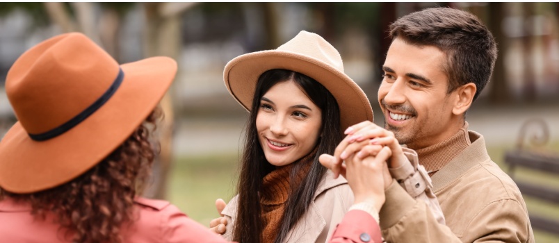 Two beautiful woman sitting on bench with man