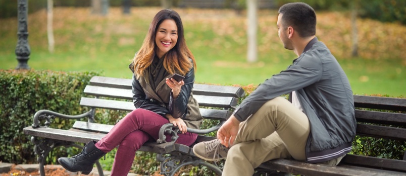 Young couple sitting on bench talking to each other