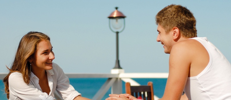 Happy couple sitting together beach side