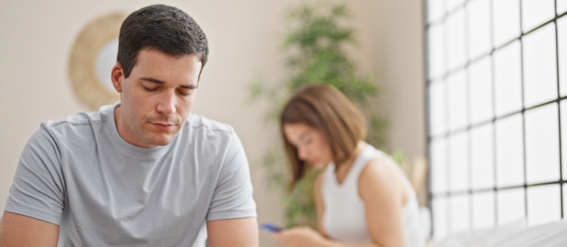 Man and woman minding their own business while sitting on the bed