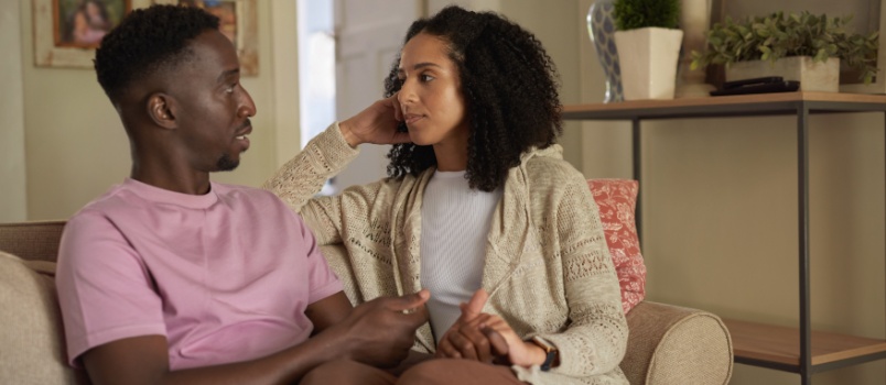 Couple sitting on couch talking to each other