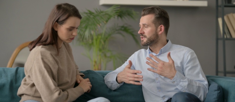 Couple sitting on couch talking to each other