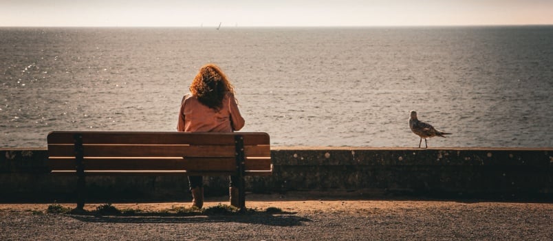 Woman sitting on bench near beach