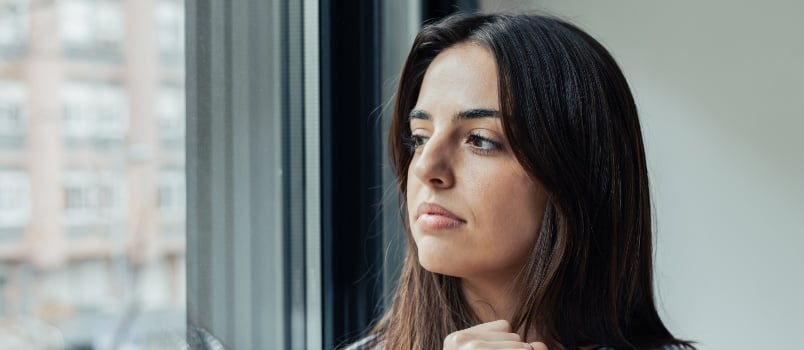 Worried woman looking outside of window