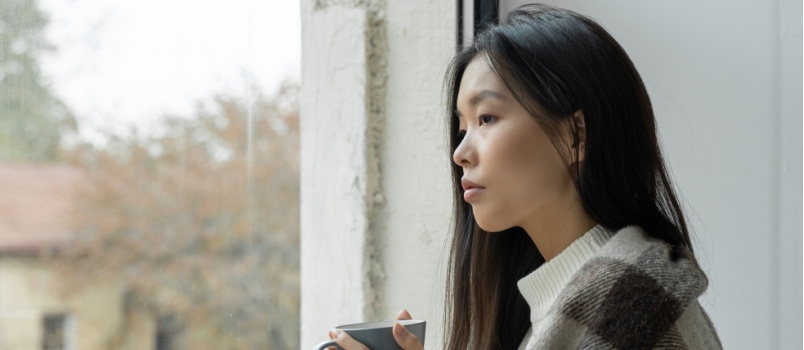 Young woman standing beside window