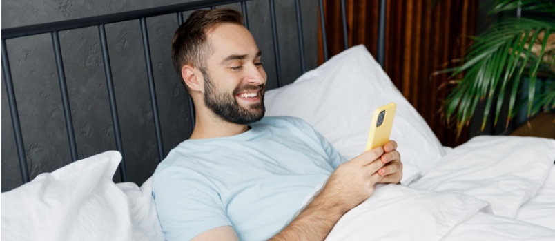 Man laying on bed using smartphone